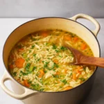 Chicken Orzo Soup in a rustic bowl with fresh parsley and bread.
