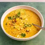 Mexican Street Corn Soup in a bowl topped with cotija, crema, and lime