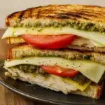 Turkey Pesto Sandwich with melted cheese, pesto, and avocado on sourdough bread