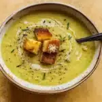 Creamy zucchini soup in rustic bowl with herbs