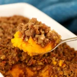 Sweet potato casserole with pecan praline topping in a rustic dish