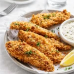 Crispy oven baked chicken tenders on a plate with dipping sauce