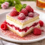 A close-up of a White Chocolate Raspberry Tiramisu slice showing pink and white layers.